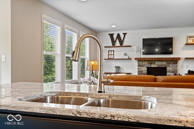11322 Sea Side Ct, Fishers, IN 46040 - kitchen featuring light stone countertops, a stone fireplace, and open floor plan