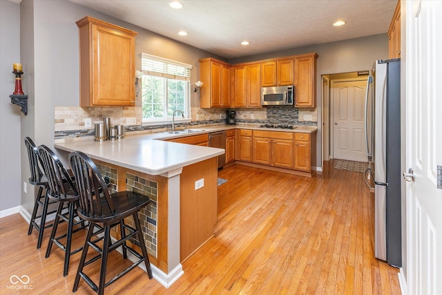 13059 Cirrus Dr, Fishers, IN 46037 - kitchen featuring stainless steel appliances, a peninsula, decorative backsplash, recessed lighting, and light wood-style floors