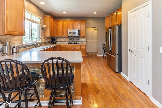 13059 Cirrus Dr, Fishers, IN 46037 - kitchen with appliances with stainless steel finishes, a peninsula, light wood-style floors, recessed lighting, and decorative backsplash