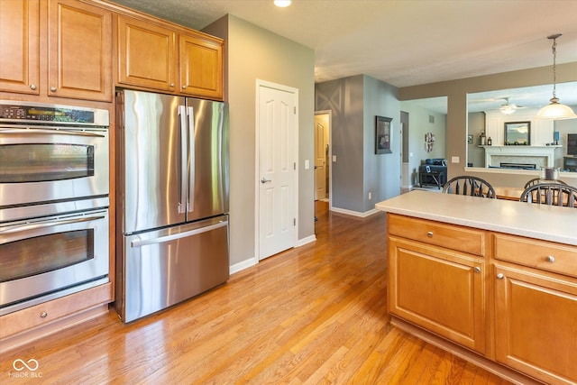 13059 Cirrus Dr, Fishers, IN 46037 - kitchen featuring appliances with stainless steel finishes, brown cabinetry, light wood-style flooring, and pendant lighting