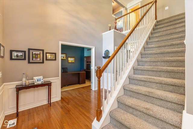 13059 Cirrus Dr, Fishers, IN 46037 - staircase featuring wood finished floors, a towering ceiling, and a wainscoted wall