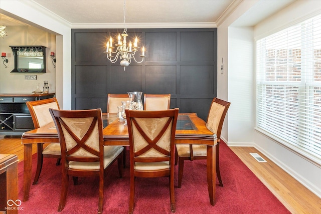 13059 Cirrus Dr, Fishers, IN 46037 - dining space with a chandelier, crown molding, wood finished floors, and a decorative wall