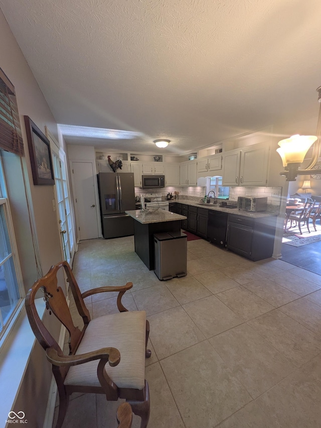 7327 Newbury Ct, Fishers, IN 46038 - kitchen with stainless steel appliances, backsplash, white cabinetry, a kitchen island, and a textured ceiling