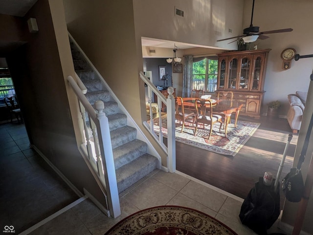 7327 Newbury Ct, Fishers, IN 46038 - stairs featuring a high ceiling, ceiling fan, tile patterned floors, and a chandelier