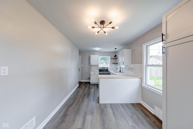 3748 N Olney St, Indianapolis, IN 46218 - kitchen featuring stainless steel electric stove, a chandelier, white cabinetry, wood finished floors, and light countertops