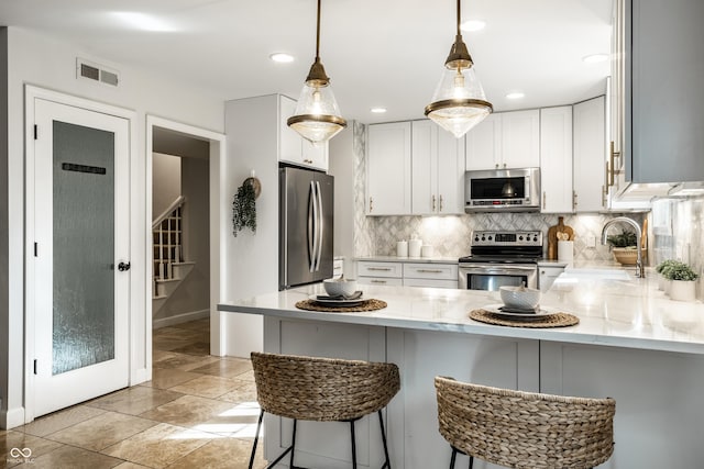 8627 Emerald Ln, Indianapolis, IN 46260 - kitchen featuring stainless steel appliances, a peninsula, decorative backsplash, white cabinets, and hanging light fixtures