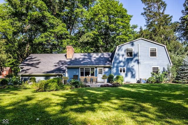 8627 Emerald Ln, Indianapolis, IN 46260 - rear view of house featuring a yard, a chimney, a patio, a gambrel roof, and a shingled roof