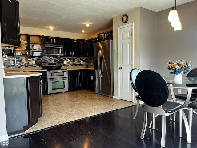1646 N Nieman Dr, Greensburg, IN 47240 - kitchen with stainless steel appliances, dark cabinets, backsplash, light countertops, and a textured ceiling