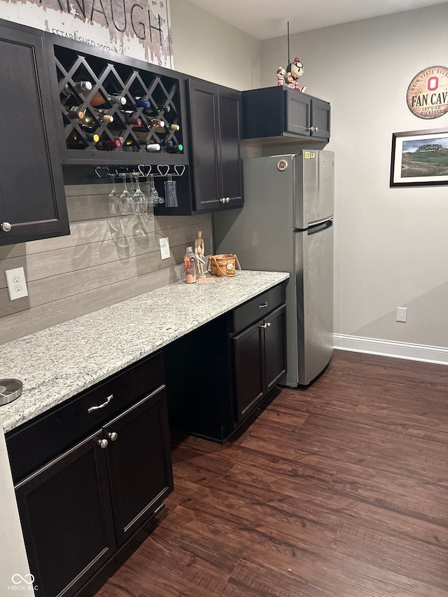 12059 Chapelwood Dr, Fishers, IN 46037 - kitchen featuring freestanding refrigerator, backsplash, dark wood-style floors, dark cabinetry, and light stone counters