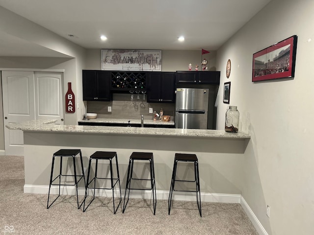 12059 Chapelwood Dr, Fishers, IN 46037 - kitchen with freestanding refrigerator, dark cabinets, a breakfast bar area, light carpet, and recessed lighting