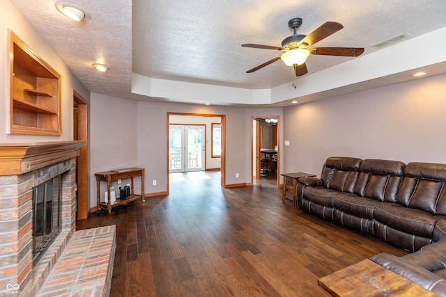 9437 N County Road 225 E, Pittsboro, IN 46167 - living area with a textured ceiling, dark wood-type flooring, ceiling fan, a brick fireplace, and a raised ceiling