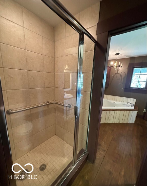 98 E Smithville Rd, Bloomington, IN 47401 - full bathroom with wood finished floors, a shower stall, a garden tub, and a chandelier