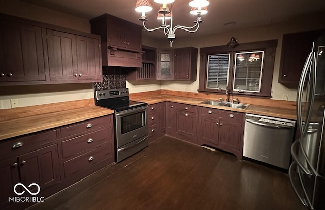 98 E Smithville Rd, Bloomington, IN 47401 - kitchen with appliances with stainless steel finishes, under cabinet range hood, a chandelier, dark wood-style floors, and wooden counters