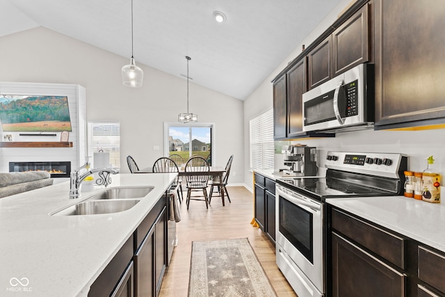1448 Willow Tree Ln, Sheridan, IN 46069 - kitchen with stainless steel appliances, light wood finished floors, pendant lighting, dark brown cabinetry, and a large fireplace