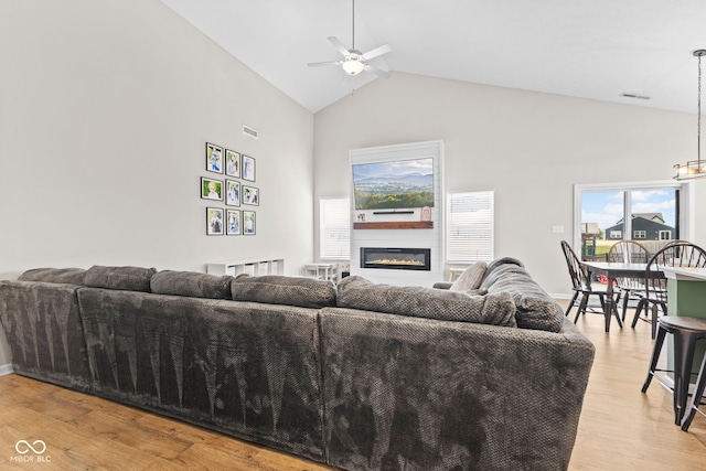 1448 Willow Tree Ln, Sheridan, IN 46069 - living room with a ceiling fan, high vaulted ceiling, a glass covered fireplace, light wood-type flooring, and plenty of natural light