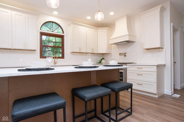 10630 Thorny Rdg Trce, Fishers, IN 46037 - kitchen with custom range hood, a breakfast bar area, white cabinetry, light countertops, and recessed lighting