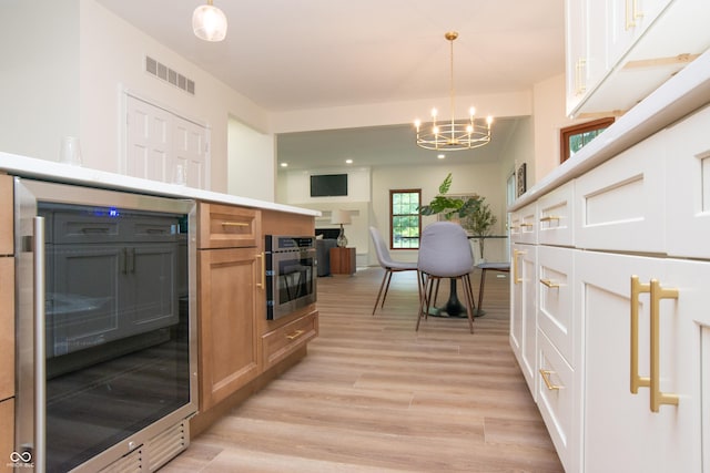 10630 Thorny Rdg Trce, Fishers, IN 46037 - kitchen with a chandelier, light wood-type flooring, wine cooler, oven, and decorative light fixtures