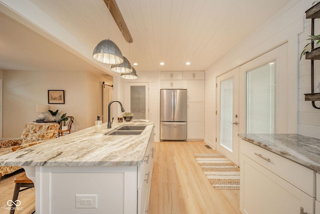 107 Pasadena Rd, Noblesville, IN 46062 - kitchen with freestanding refrigerator, light wood-style flooring, white cabinets, a breakfast bar area, and a barn door