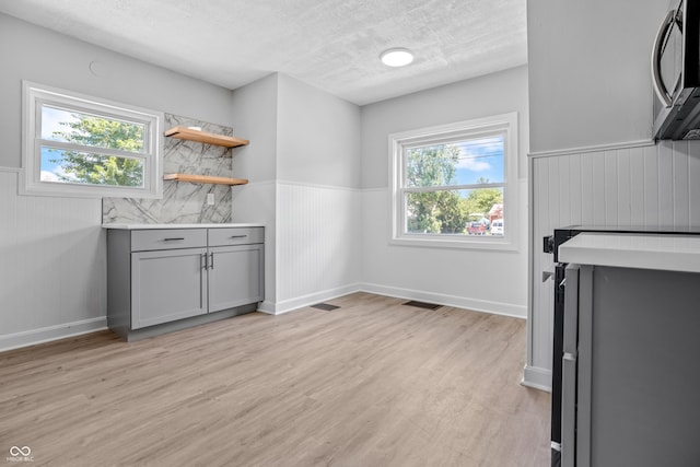 184 N Post Rd, Indianapolis, IN 46219 - bar area with stainless steel microwave, a wainscoted wall, light wood-style floors, and a textured ceiling