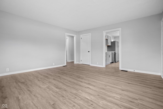 184 N Post Rd, Indianapolis, IN 46219 - unfurnished living room with light wood-style floors and baseboards