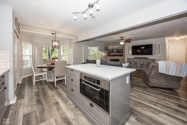 14126 Stonewood Pl, Fishers, IN 46037 - kitchen with a stone fireplace, light countertops, gray cabinetry, a ceiling fan, and dark wood-style floors