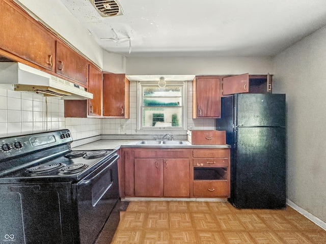 3505 N Emerson Ave, Indianapolis, IN 46218 - kitchen with black appliances, under cabinet range hood, light countertops, backsplash, and brown cabinets