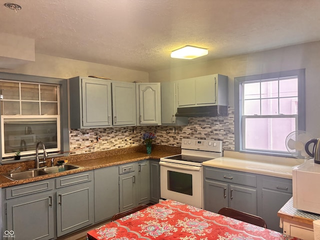 543 N Oakland Ave, Indianapolis, IN 46201 - kitchen featuring white range with electric cooktop, under cabinet range hood, gray cabinetry, backsplash, and a textured ceiling