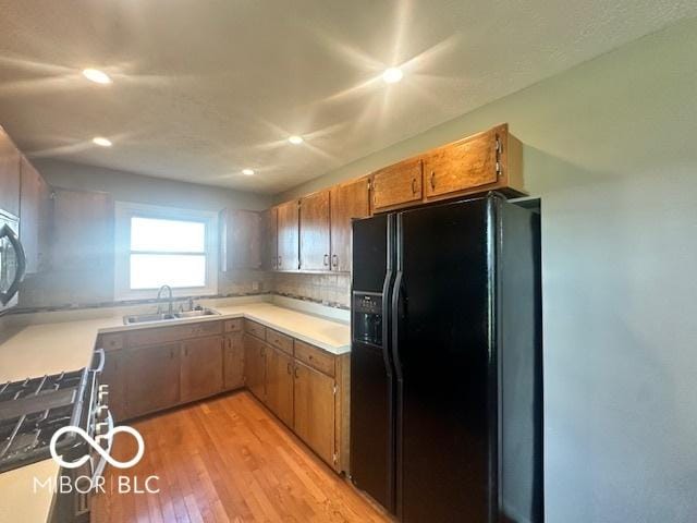 9490 N Keith Dr W, Columbus, IN 47203 - kitchen with black fridge, light wood finished floors, recessed lighting, stove, and brown cabinets