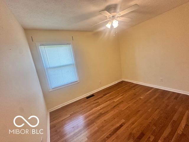 9490 N Keith Dr W, Columbus, IN 47203 - spare room featuring dark wood finished floors, ceiling fan, and a textured ceiling