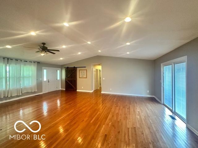 9490 N Keith Dr W, Columbus, IN 47203 - unfurnished living room with a barn door, vaulted ceiling, wood finished floors, and ceiling fan