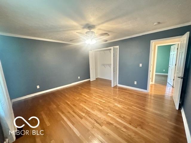 9490 N Keith Dr W, Columbus, IN 47203 - unfurnished bedroom with wood finished floors, crown molding, a closet, and ceiling fan