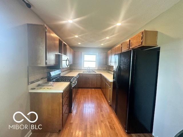 9490 N Keith Dr W, Columbus, IN 47203 - kitchen with black refrigerator with ice dispenser, stainless steel gas stove, light countertops, light wood-style floors, and recessed lighting