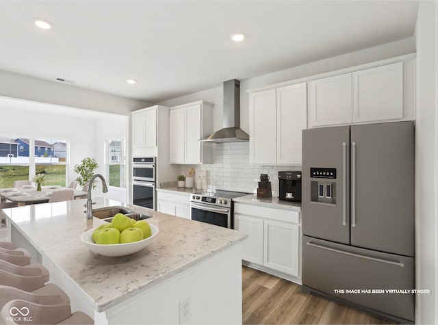 1186 Vera Blvd, Danville, IN 46122 - kitchen with stainless steel appliances, wall chimney exhaust hood, white cabinetry, light wood finished floors, and recessed lighting