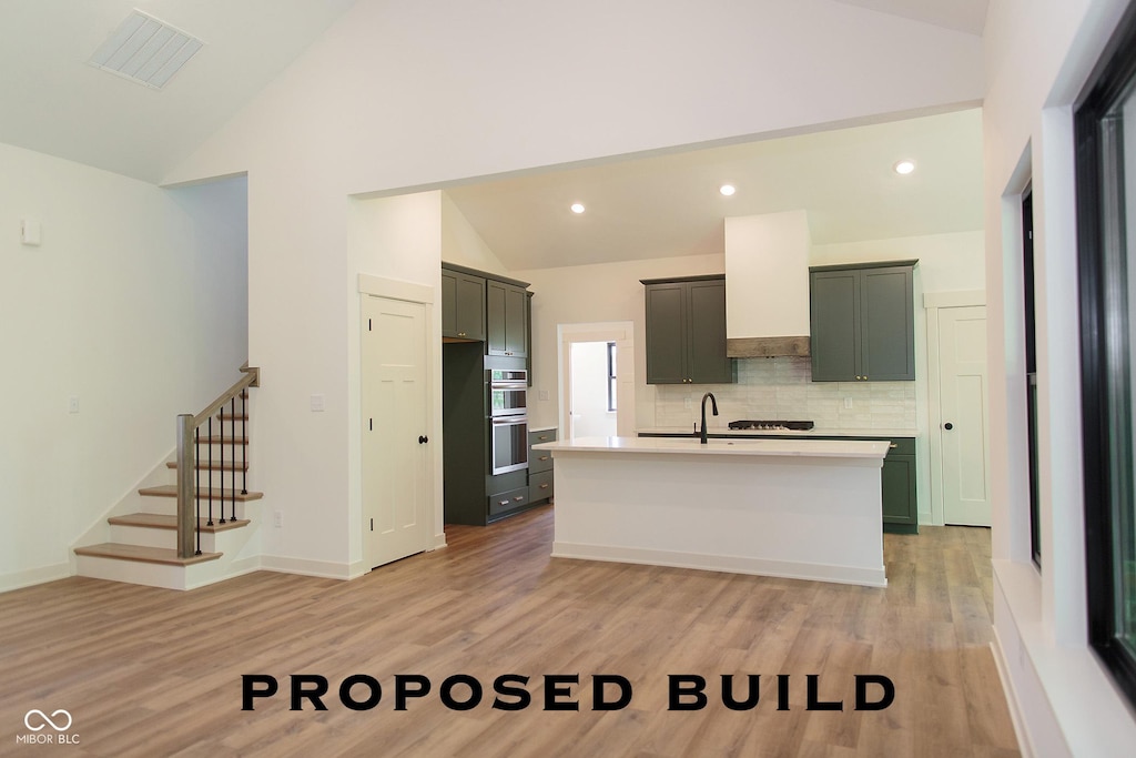 LOT76 Egs Blvd, Batesville, IN 47006 - kitchen featuring light countertops, light wood-style floors, decorative backsplash, a center island with sink, and high vaulted ceiling