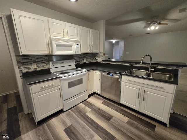 4293 Blue Spruce Ct, Greenwood, IN 46143 - kitchen featuring white appliances, dark countertops, a peninsula, dark wood-style flooring, and white cabinetry