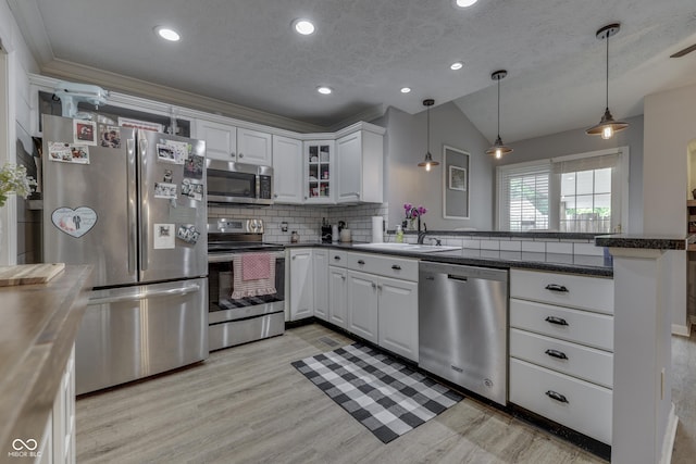 7444 Melanie Ln, Indianapolis, IN 46217 - kitchen with stainless steel appliances, a peninsula, vaulted ceiling, tasteful backsplash, and light wood-type flooring