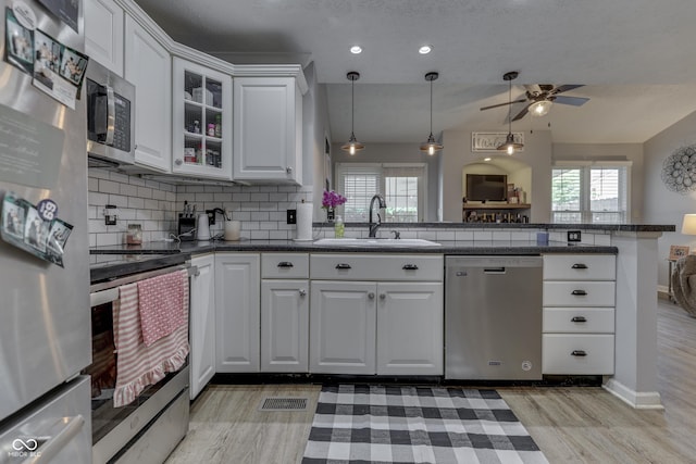 7444 Melanie Ln, Indianapolis, IN 46217 - kitchen featuring appliances with stainless steel finishes, ceiling fan, light wood finished floors, tasteful backsplash, and plenty of natural light