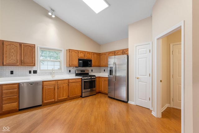 11628 Coastal Way, Indianapolis, IN 46229 - kitchen with stainless steel appliances, backsplash, light wood-style flooring, brown cabinets, and high vaulted ceiling