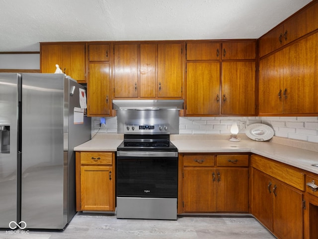5530 Skyridge Dr, Indianapolis, IN 46250 - kitchen with appliances with stainless steel finishes, under cabinet range hood, brown cabinetry, light countertops, and a textured ceiling