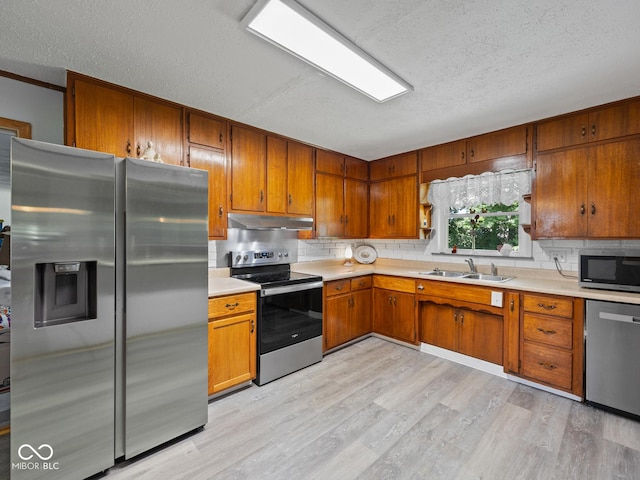 5530 Skyridge Dr, Indianapolis, IN 46250 - kitchen with appliances with stainless steel finishes, a textured ceiling, light countertops, brown cabinets, and light wood-style flooring
