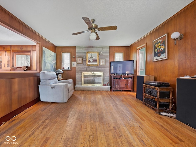 5530 Skyridge Dr, Indianapolis, IN 46250 - living area featuring light wood-style floors, a large fireplace, wood walls, ceiling fan, and ornamental molding