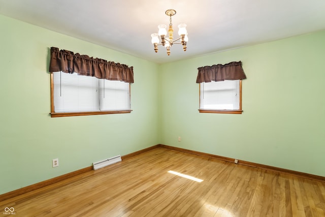 2635 15th St, Columbus, IN 47201 - spare room featuring a baseboard radiator, a chandelier, and light wood-type flooring