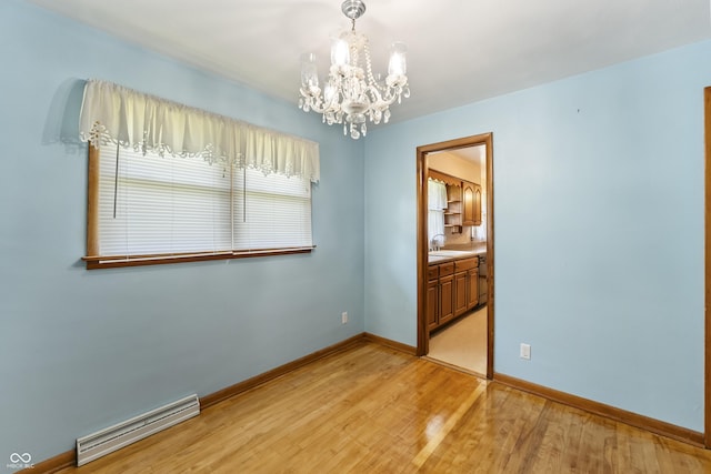 2635 15th St, Columbus, IN 47201 - empty room featuring a chandelier, light wood-style floors, and a baseboard heating unit