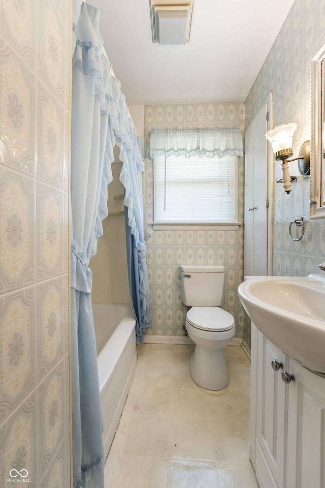 2635 15th St, Columbus, IN 47201 - full bathroom with wallpapered walls, vanity, and shower / bath combo with shower curtain