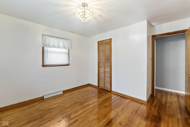 2635 15th St, Columbus, IN 47201 - unfurnished bedroom featuring a chandelier, a closet, wood finished floors, and a baseboard radiator
