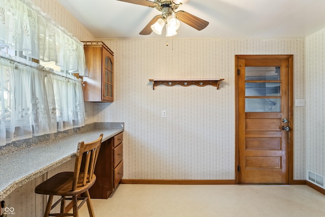 2635 15th St, Columbus, IN 47201 - kitchen with brown cabinets, glass insert cabinets, a ceiling fan, and a kitchen bar