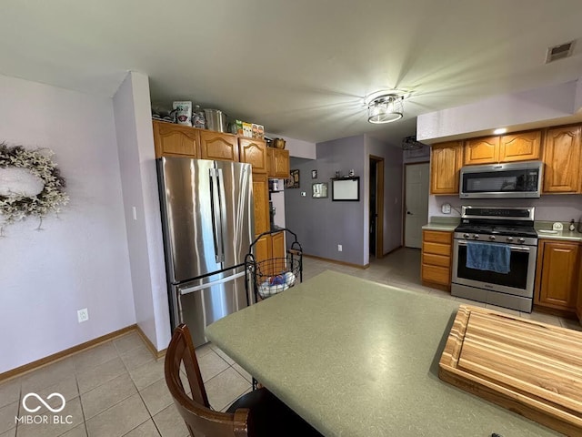 1214 Lindsey Ln, Lebanon, IN 46052 - kitchen featuring appliances with stainless steel finishes, light tile patterned floors, brown cabinets, and light countertops
