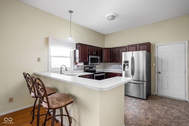 10721 Chesapeake Dr S, Indianapolis, IN 46236 - kitchen featuring appliances with stainless steel finishes, a peninsula, light countertops, a breakfast bar area, and pendant lighting