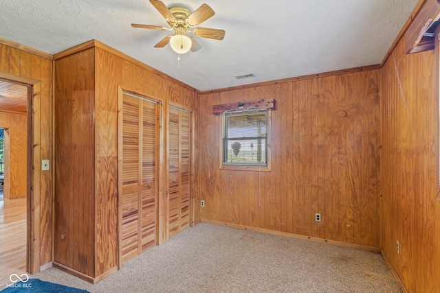 8701 E Splinter Ridge Rd, Madison, IN 47250 - unfurnished bedroom featuring wood walls, two closets, carpet flooring, and a ceiling fan
