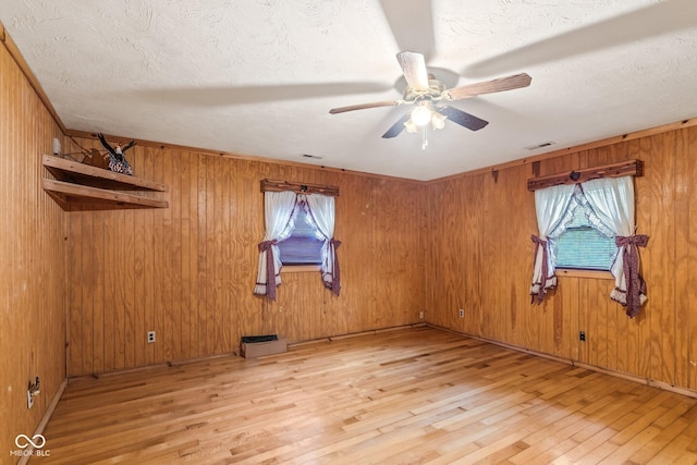 8701 E Splinter Ridge Rd, Madison, IN 47250 - unfurnished room with light wood-style floors, a ceiling fan, wooden walls, a textured ceiling, and baseboard heating